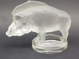 une figurine en verre transparent représentant un taureau, posée sur un socle