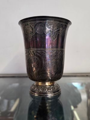 un vase en argent posé sur une table en verre