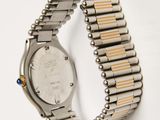 a close up of a watch on a metal bracelet on a white surface