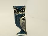 une petite figurine de chouette bleue posée sur une surface blanche