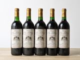 four bottles of wine are lined up on a wooden table