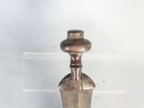a silver vase that is on a clear shelf