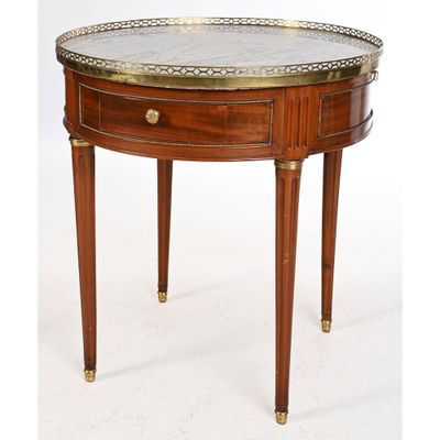 une petite table ronde avec un plateau en marbre et des finitions en laiton