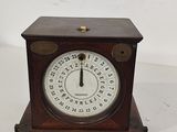 une petite horloge en bois posée sur une surface blanche