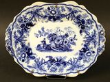 une vieille assiette bleue et blanche sur laquelle est représenté un homme dans un bateau