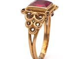 a close up of a gold ring with a red stone