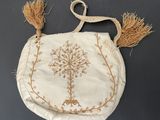 a white purse with a tree on the front and tassels hanging from it