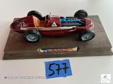 une petite maquette de voiture de course rouge posée sur un socle en bois