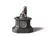 une petite statue représentant un garçon assis sur une horloge
