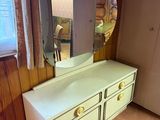 une commode blanche surmontée d'un miroir, dans une pièce