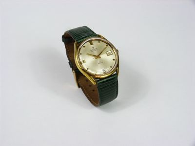 une montre en or avec un bracelet vert sur un fond blanc