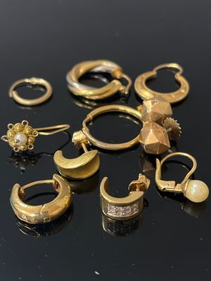 plusieurs paires de boucles d'oreilles et de bagues en or posées sur un fond noir