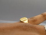 a man ' s hand with a gold signet ring on it