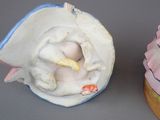two figurines of a baby in a shell on a table