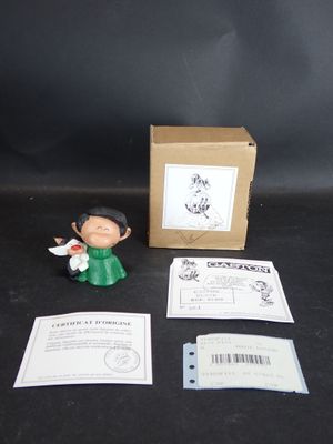 une petite figurine représentant un homme en robe verte, à côté d'une boîte