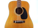 an acoustic guitar sitting on a stand against a white background