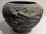 un vase noir orné d'un motif représentant un dragon