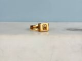 a picture of a gold signet ring on a marble surface