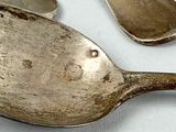 four spoons and a fork on a white table