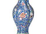 un vase bleu orné de fleurs, posé sur une surface blanche
