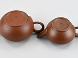 pair of brown ceramic teapots sitting on a white surface