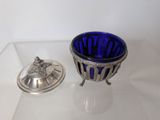 a blue glass bowl with a silver lid on a table