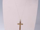 a gold cross necklace on a mannequin neck with a white background