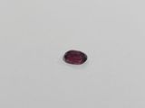 an oval shaped red garnet stone on a white surface