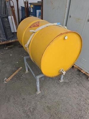 un fût jaune posé sur un support métallique dans un garage