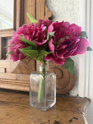 un vase en verre contenant des fleurs roses, posé sur une commode