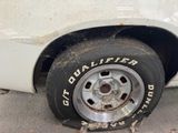 a dirty tire on the side of a white car