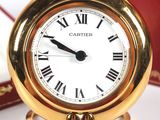 a gold clock with roman numerals and a red box