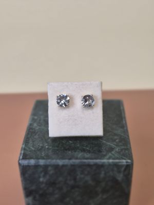 a pair of diamond earrings sitting on top of a marble block
