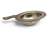 a silver bowl with a spoon in it on a white surface