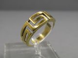 un gros plan d'une bague en or posée sur une surface transparente