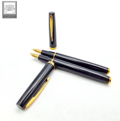 two black and gold fountain pens sitting next to each other on a white surface
