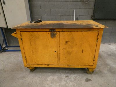 an old yellow cabinet sitting in a garage next to a brick wall