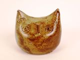 a brown and black cat figurine sitting on a white surface