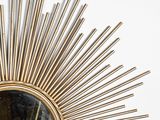 an image of a gold sunburst mirror on a white wall