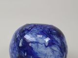 un gros plan d'une boule de verre bleue posée sur une surface blanche