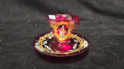 une tasse et une soucoupe en verre rouge posées sur une table noire