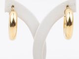 a pair of gold hoop earrings on a white stand
