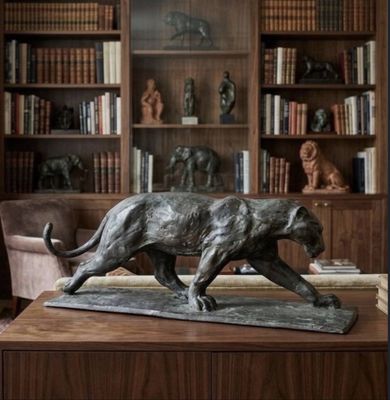 a statue of a cat on a table in a library