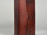 an old book with a brown cover sitting on top of a white surface