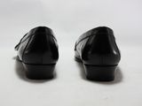 une paire de chaussures en cuir noir posées sur une surface blanche, sur fond blanc