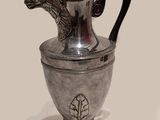 une théière en argent posée sur un socle orné d'une tête de dragon