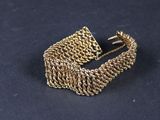 gros plan d'un bracelet en or sur une surface noire