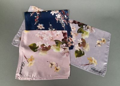three napkins with flowers and leaves on them on a table