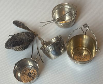 trois casseroles en métal et une passoire sont posées sur une table