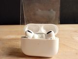 une paire d'AirPods posée dans une boîte transparente sur une table